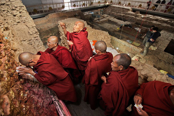 Monaci in pellegrinaggio al tempio di Lumbini. Sullo sfondo gli scavi archeologici che interessano l'area (Ira Block, National Geographic)